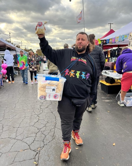 A crew member carrying the sample bin and holding up a bag at a fest