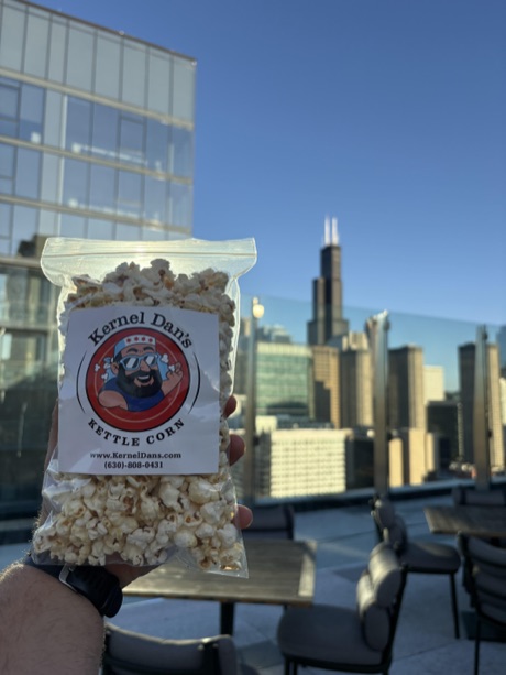 A bag of Kernel Dan's held up against the Chicago skyline