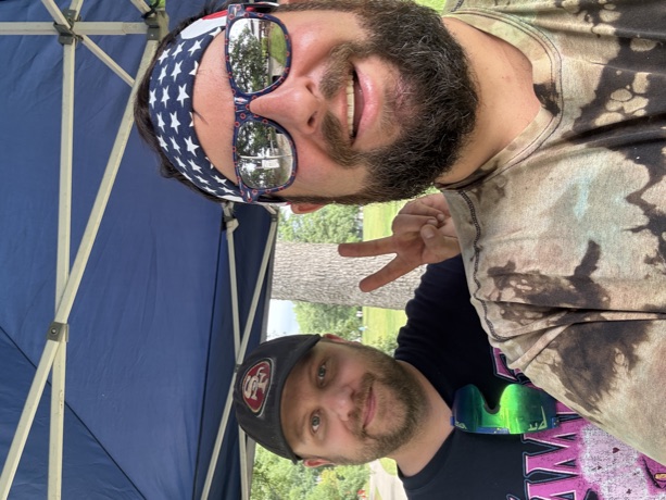 Two of the crew under the tent, one flashing a peace sign